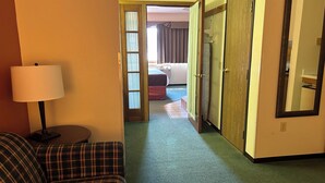 Een hotelkamer met een kamer met ruitjes patroon, een lamp, een houten garderobe en een bed met gordijn.