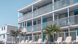 Un hotel con piscina, varios balcones y sillones de sol.