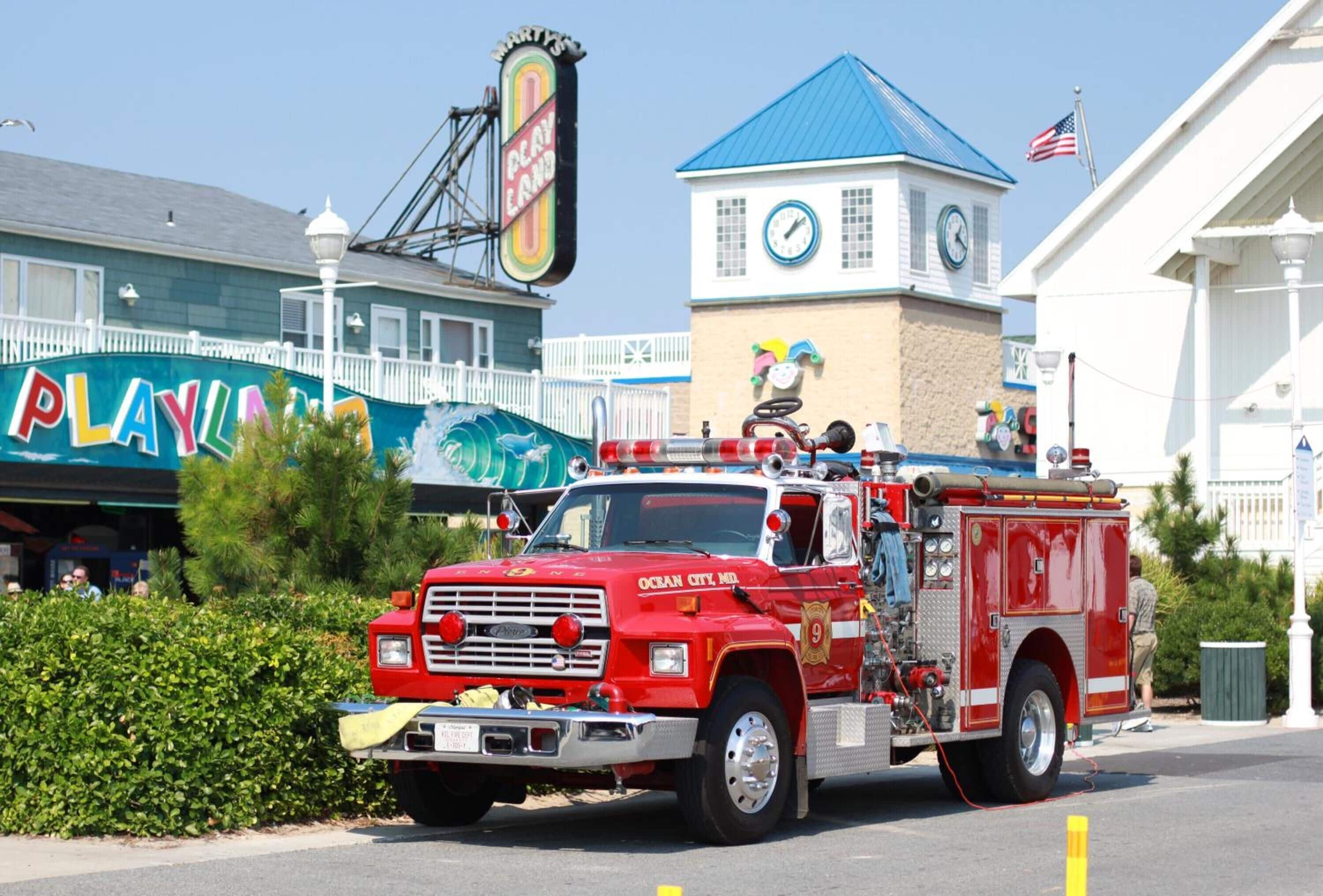 A red fire truck parked in front of a building with a clock tower and a sign that reads "PLAYLAND".