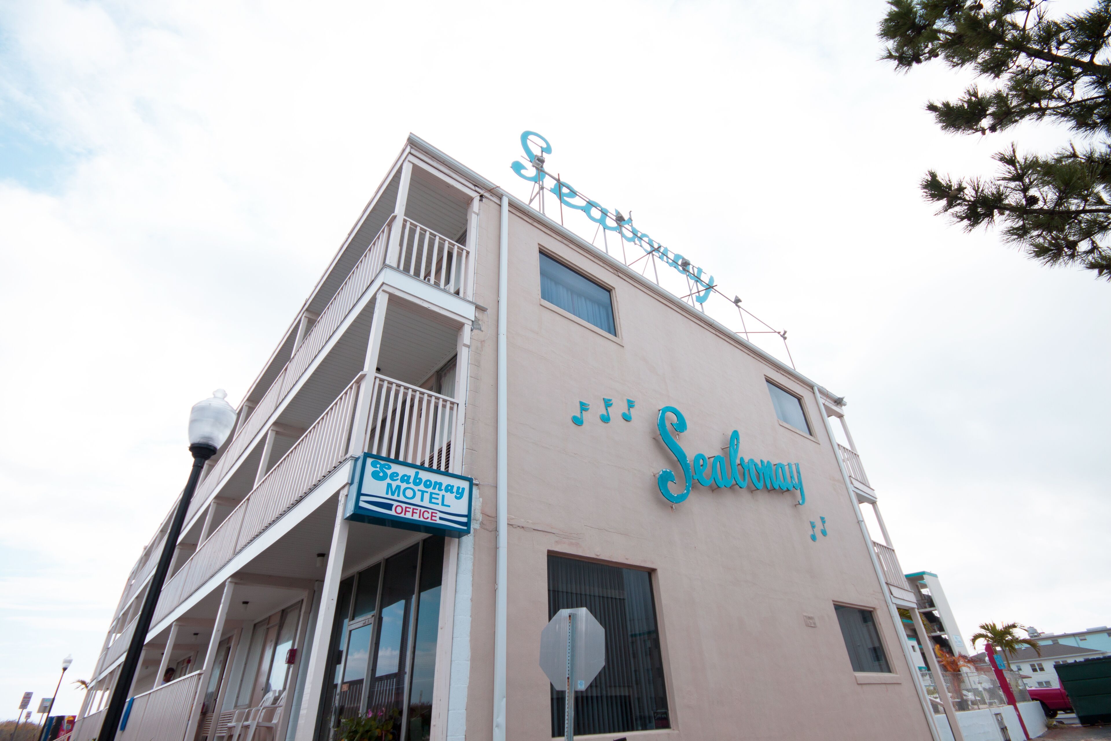 A motel building with a balcony and a sign that reads "Seasons Motel Office".