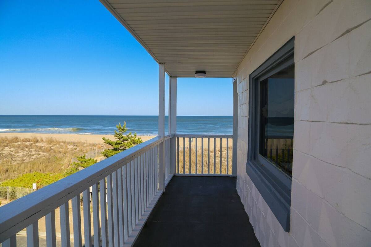A covered porch with a view of the beach and ocean.