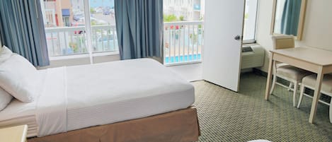 Habitación de hotel con cama, escritorio, silla y un ventanal con vistas a edificios y una piscina.