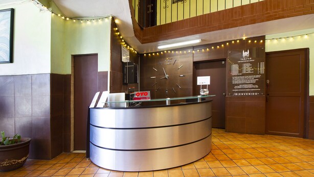 A reception desk with a clock, a sign with room rates, and a 'Bienvenido' sign. - OYO Hotel Brazil,Guadalajara,Estadio Jalisco (Guadalajara)