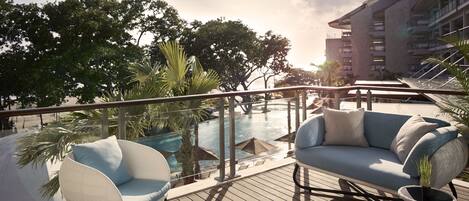 Une terrasse avec coin salon extérieur, une piscine et une vue sur un immeuble doté de balcons.