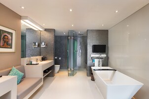 A modern bathroom with a glass-enclosed shower, a white bathtub, and a vanity with a mirror.
