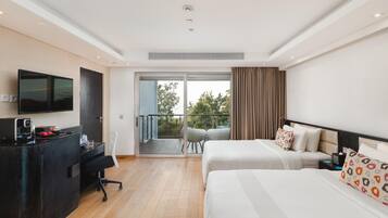 A hotel room with two beds, a desk with a flat-screen TV, a chair, and a balcony with a view of trees.