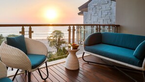 A balcony with wicker chairs, a blue sofa, and a small table with fruit and a drink. - Double-Six Luxury Hotel (Seminyak)