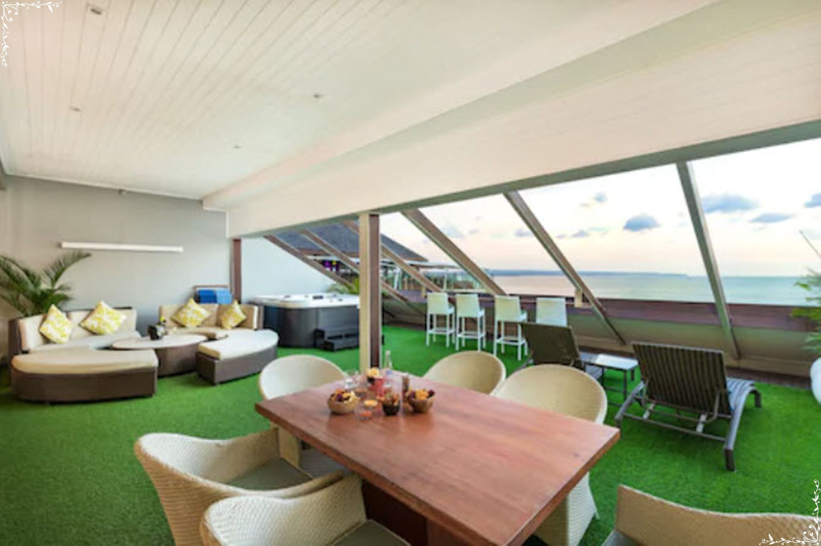 Uma área de estar moderna ao ar livre, com mesa de madeira, cadeiras de vime e vista para o oceano.