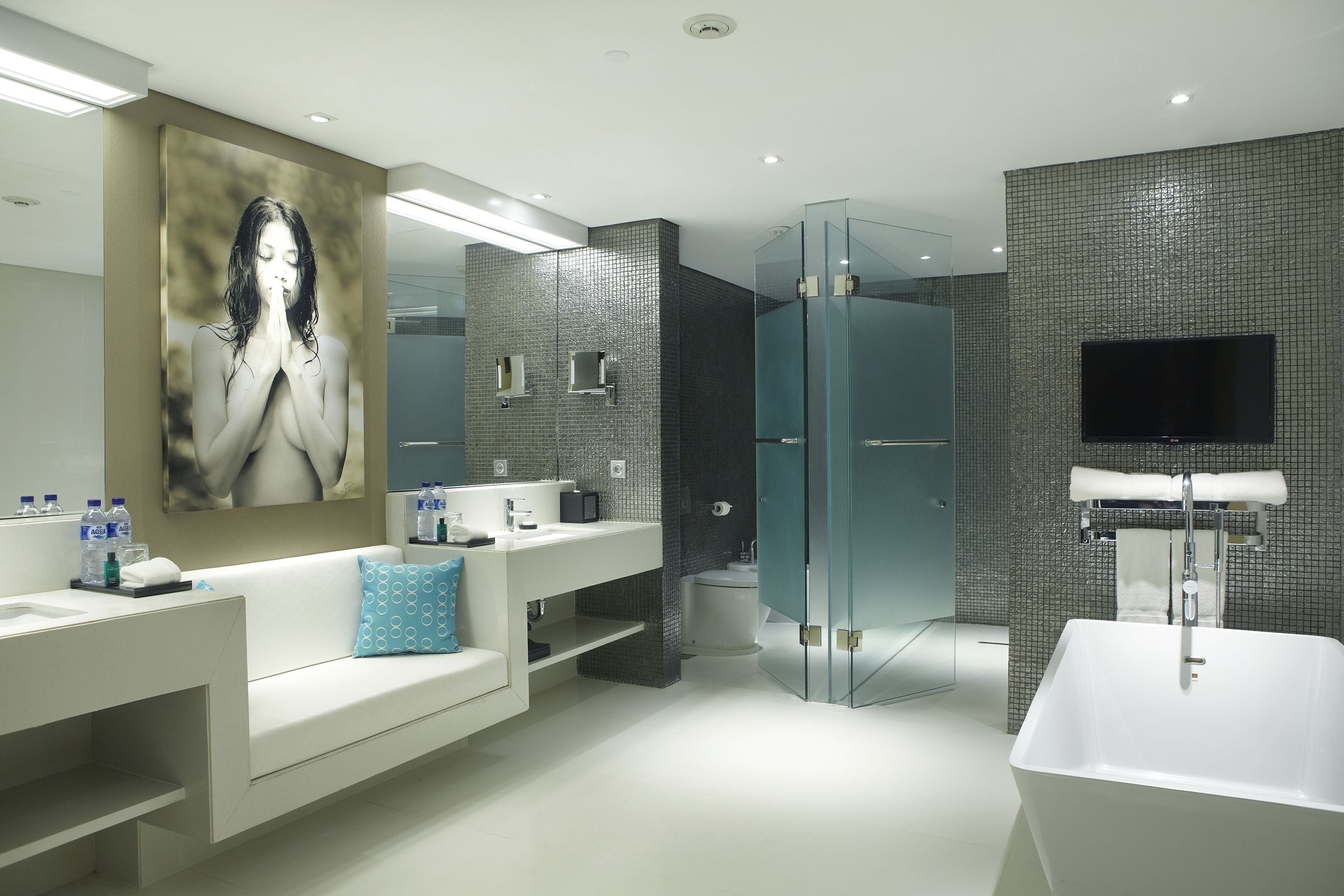 A modern bathroom with a large mirror, a bathtub, a glass shower enclosure, and a white sink with a towel rack.