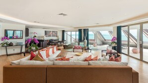 A spacious living area with a large sofa, a dining table, and a kitchen in the background. - Double-Six Luxury Hotel (Seminyak)