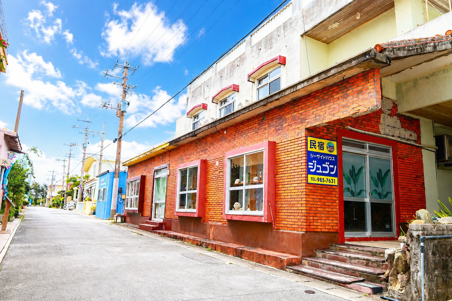 A red brick building with a blue storefront and a visible telephone number.