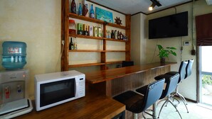 A bar area with a wooden counter, a microwave, and a water dispenser.