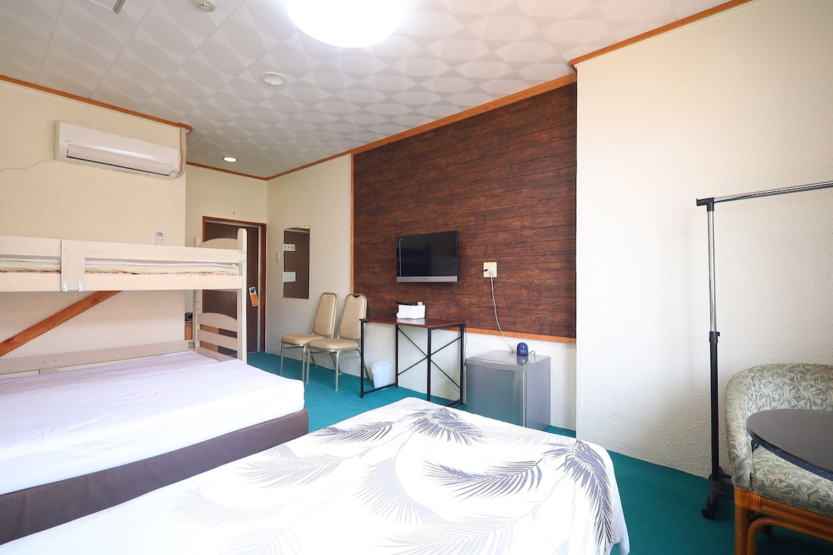 Ett hotellrum med våningssängar, en tv, ett skrivbord och en stol.