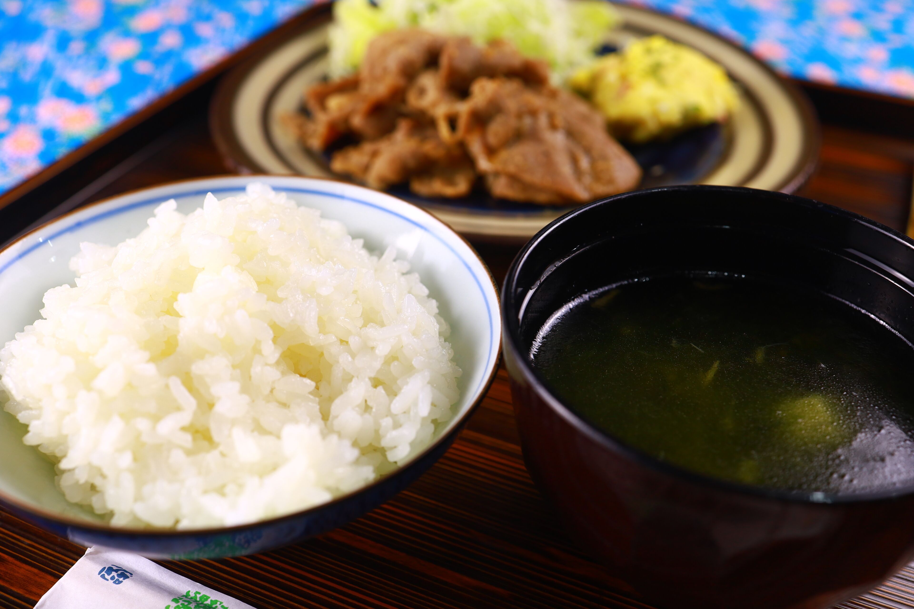 A meal with rice, soup, and meat on a tray.