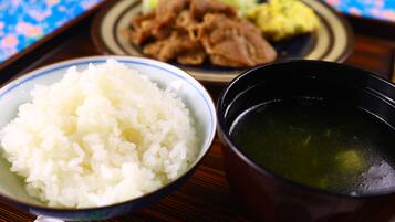 A meal with rice, soup, and meat on a tray.