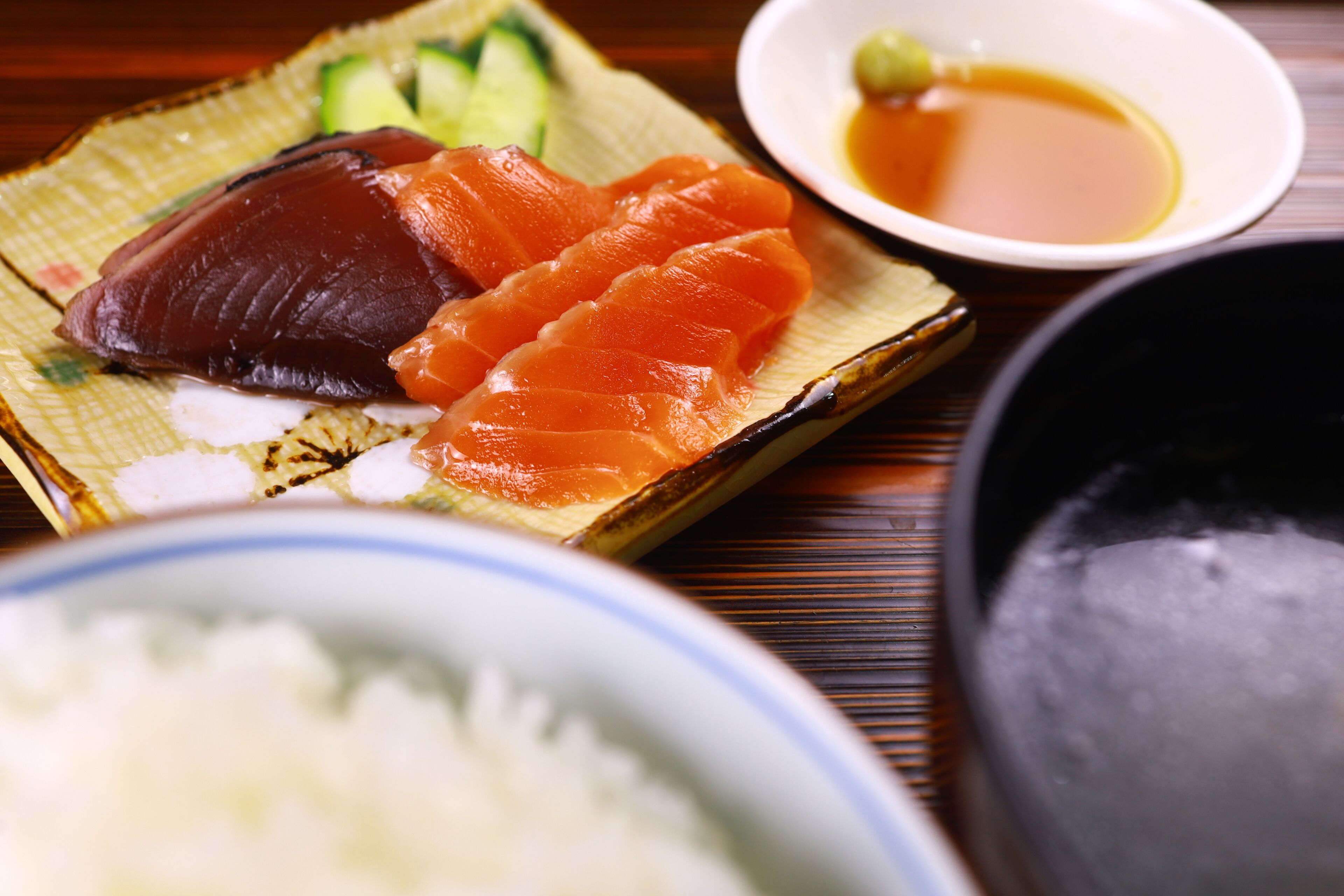 Une assiette de sushis, accompagnée d’un bol de sauce soja et de gingembre mariné.