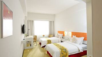 A hotel room with two beds, a desk, a chair, and a window with curtains.