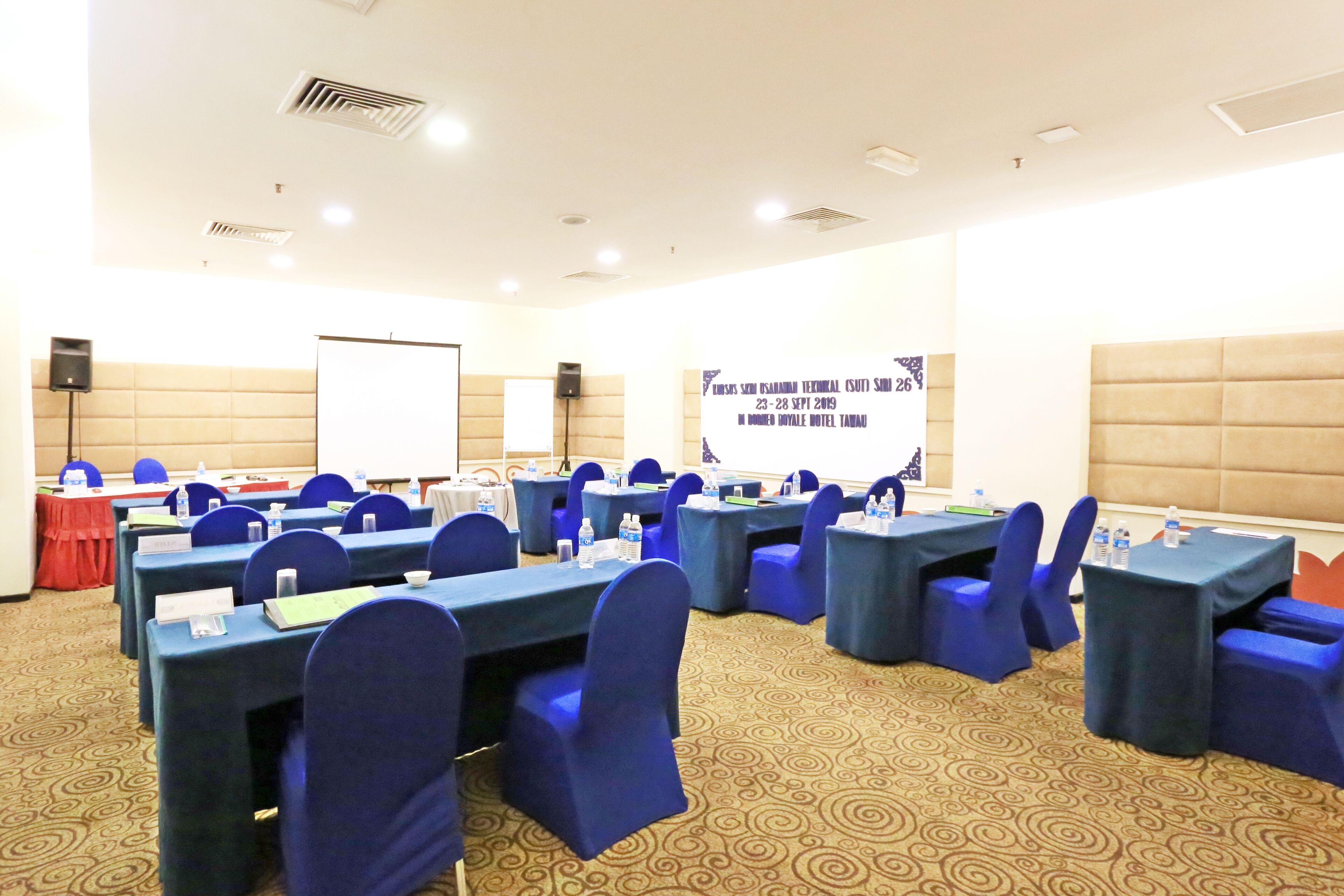 A conference room with multiple tables and chairs, equipped with nameplates and water bottles.