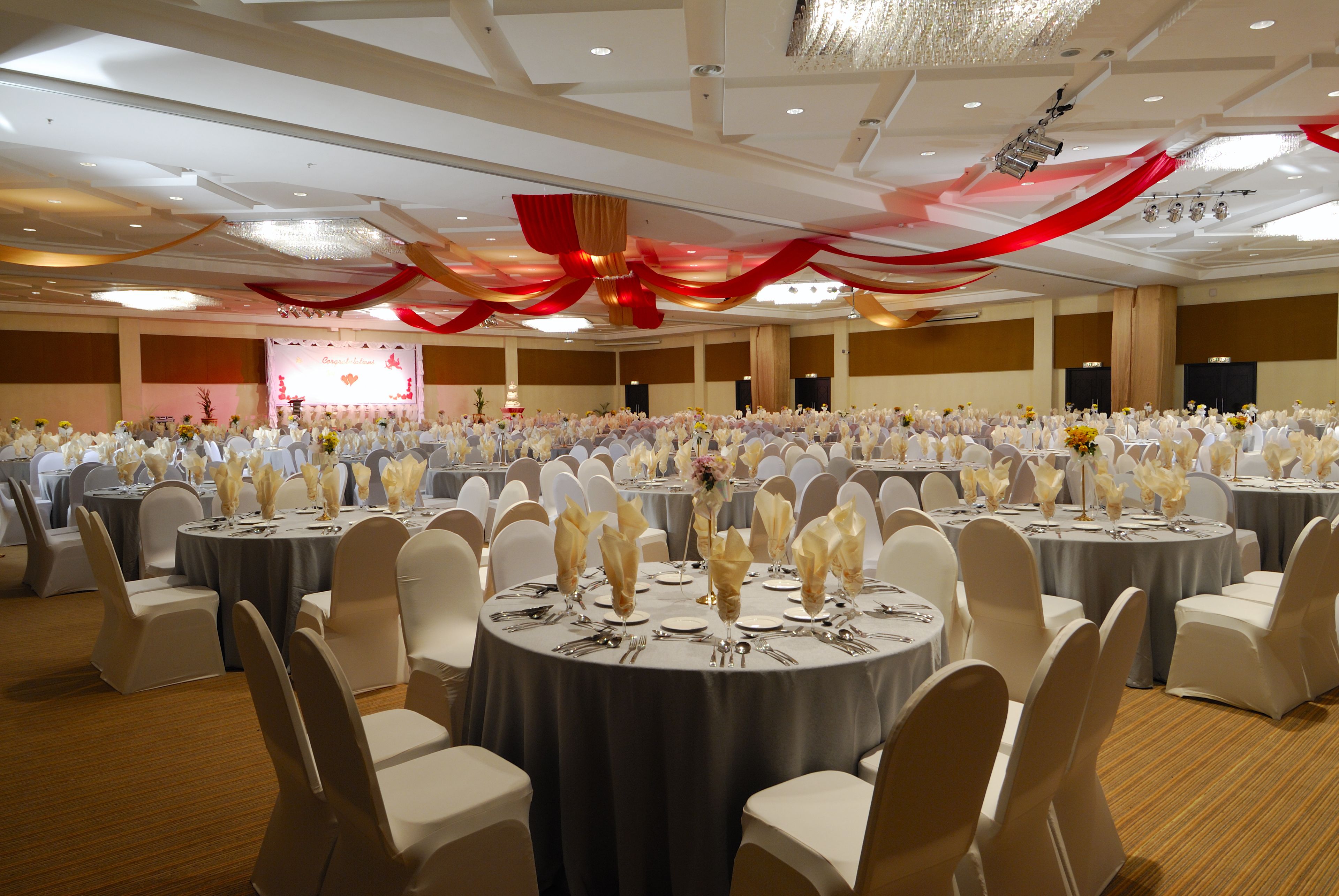 A banquet hall with round tables set for a formal event, featuring white chairs and table settings.