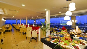 A buffet setup with various food items and a view of the cityscape through large windows. - Borneo Royale Hotel (Tawau)
