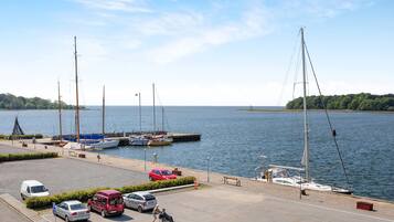 A marina with boats docked, a parking area with cars, and a clear view of the water.