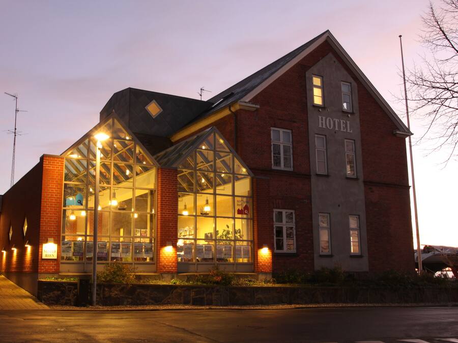 A hotel with a brick facade, large windows, and a sign indicating it is a hotel.