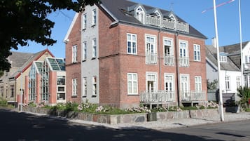 Un hotel de varios pisos con fachada de ladrillo, ventanas de marco blanco y balcones con barandillas blancas.