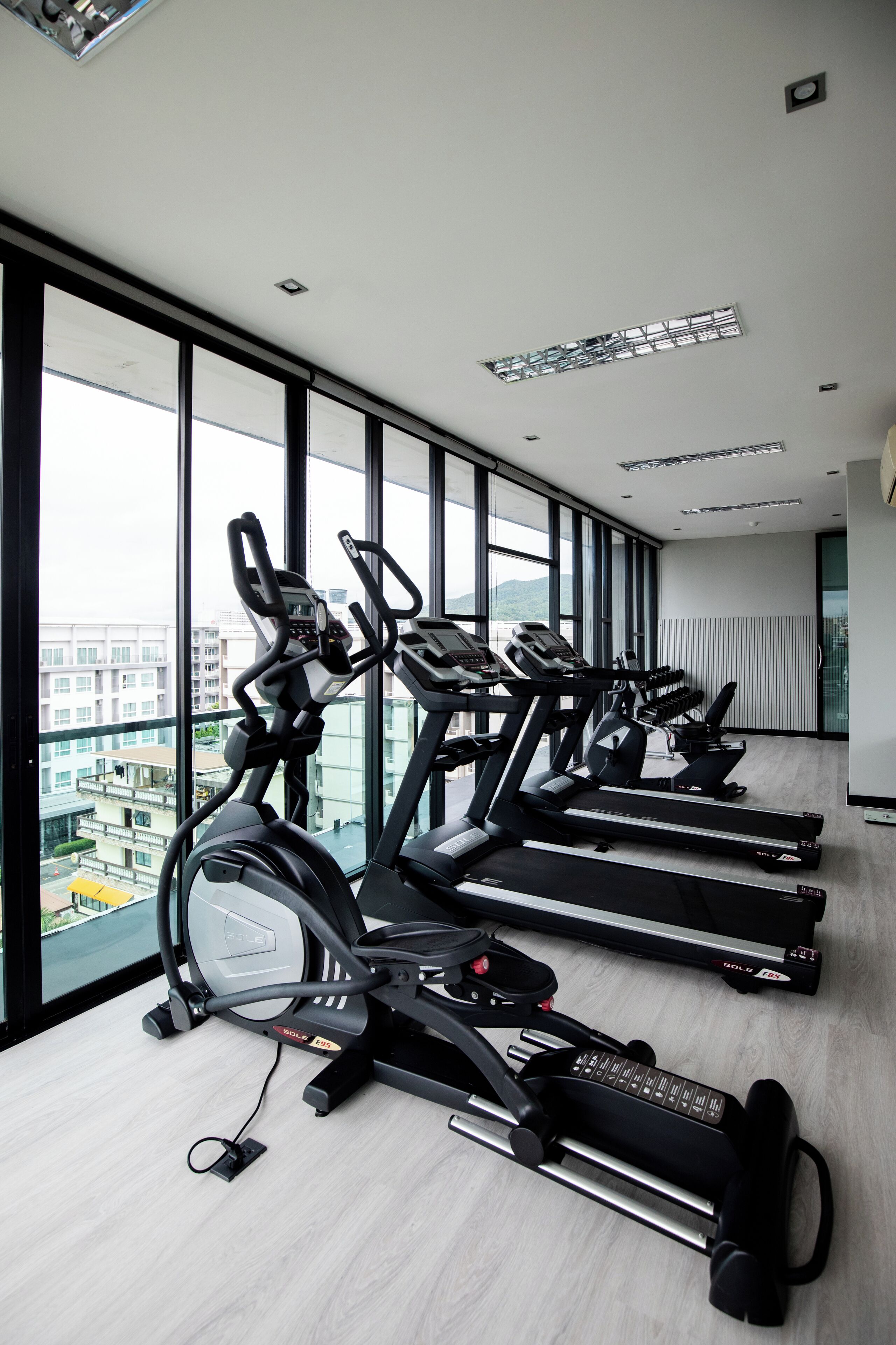 A row of stationary bikes in a modern, well-lit room with large windows offering a city view.