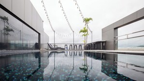 A modern indoor swimming pool with clear water, string lights, and a view of the sky. - De Chai Oriental Nimman (Chiang Mai)