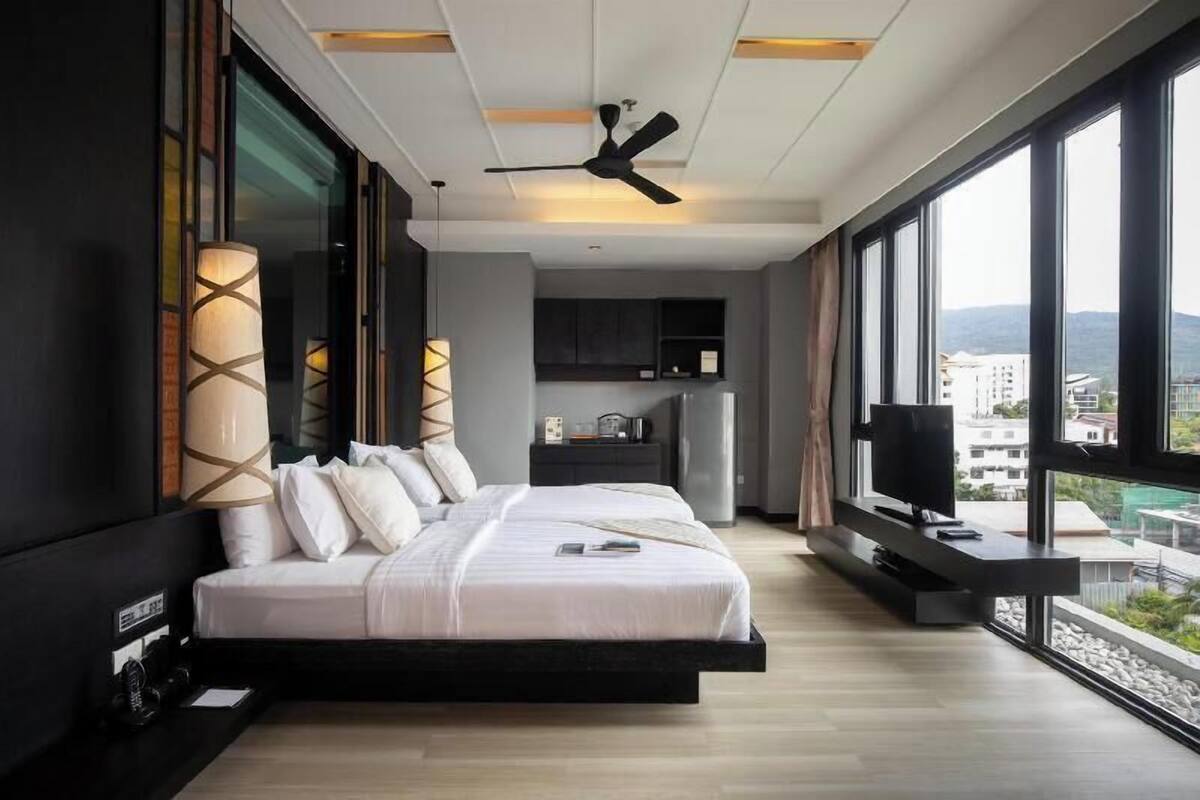 A modern bedroom with a large bed, a TV, and a view of the city.