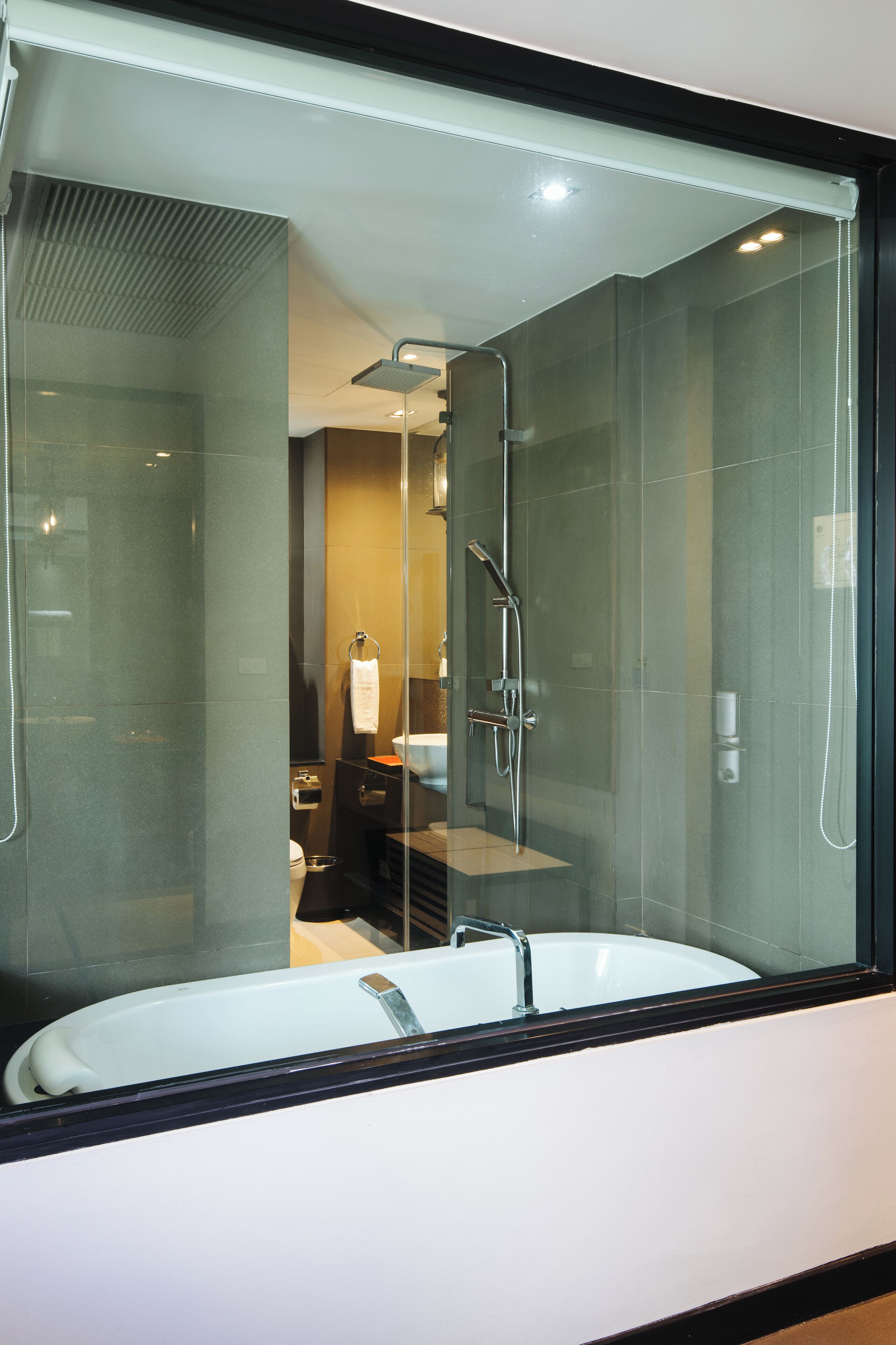 Un baño moderno con ducha de vidrio, lavamanos blanco y toallero visible.