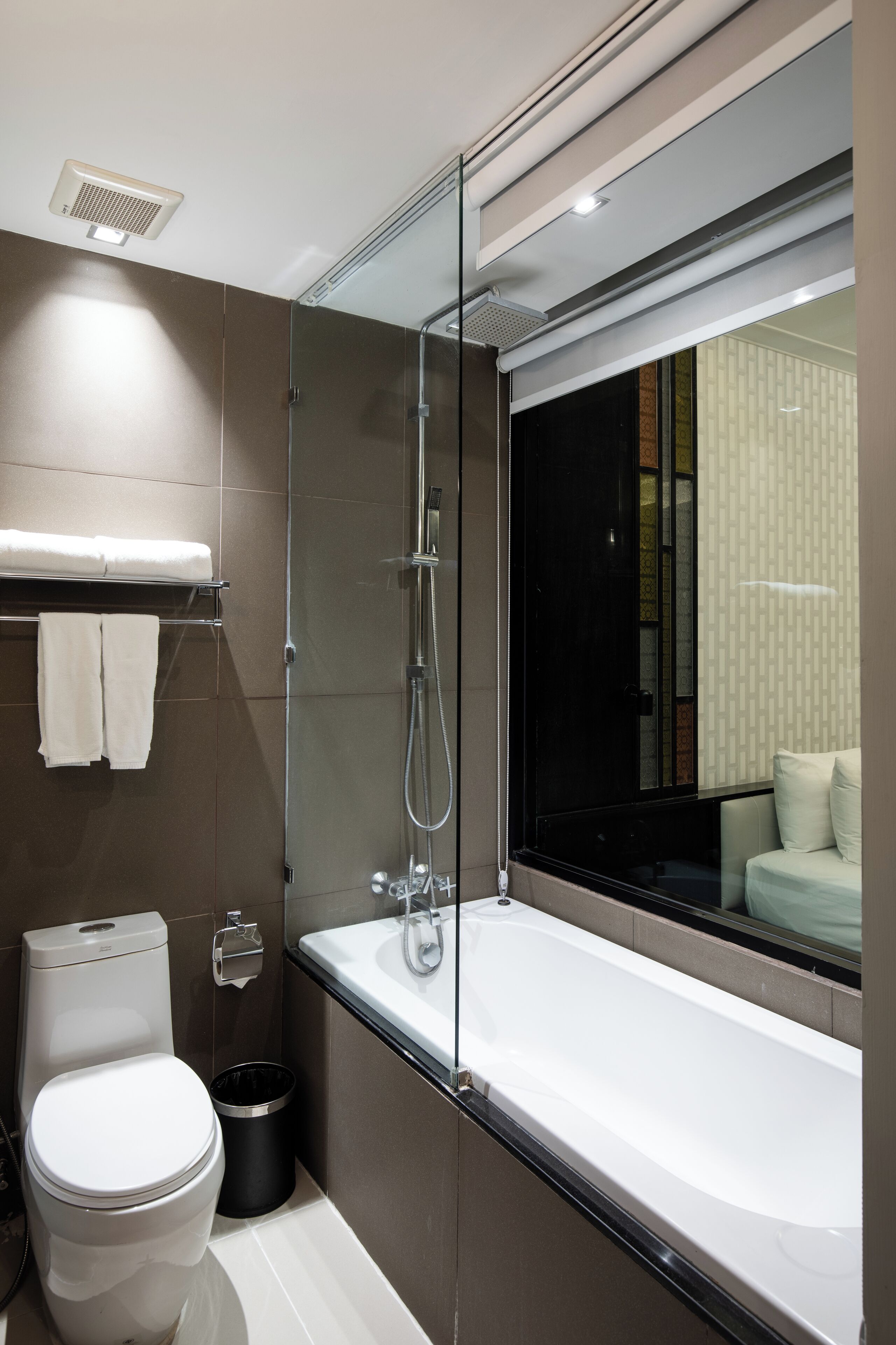 A modern bathroom with a glass-enclosed shower, a white toilet, and a bathtub.