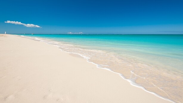 A beach with clear turquoise water and a sandy shore. - Island Club Turks (Providenciales)