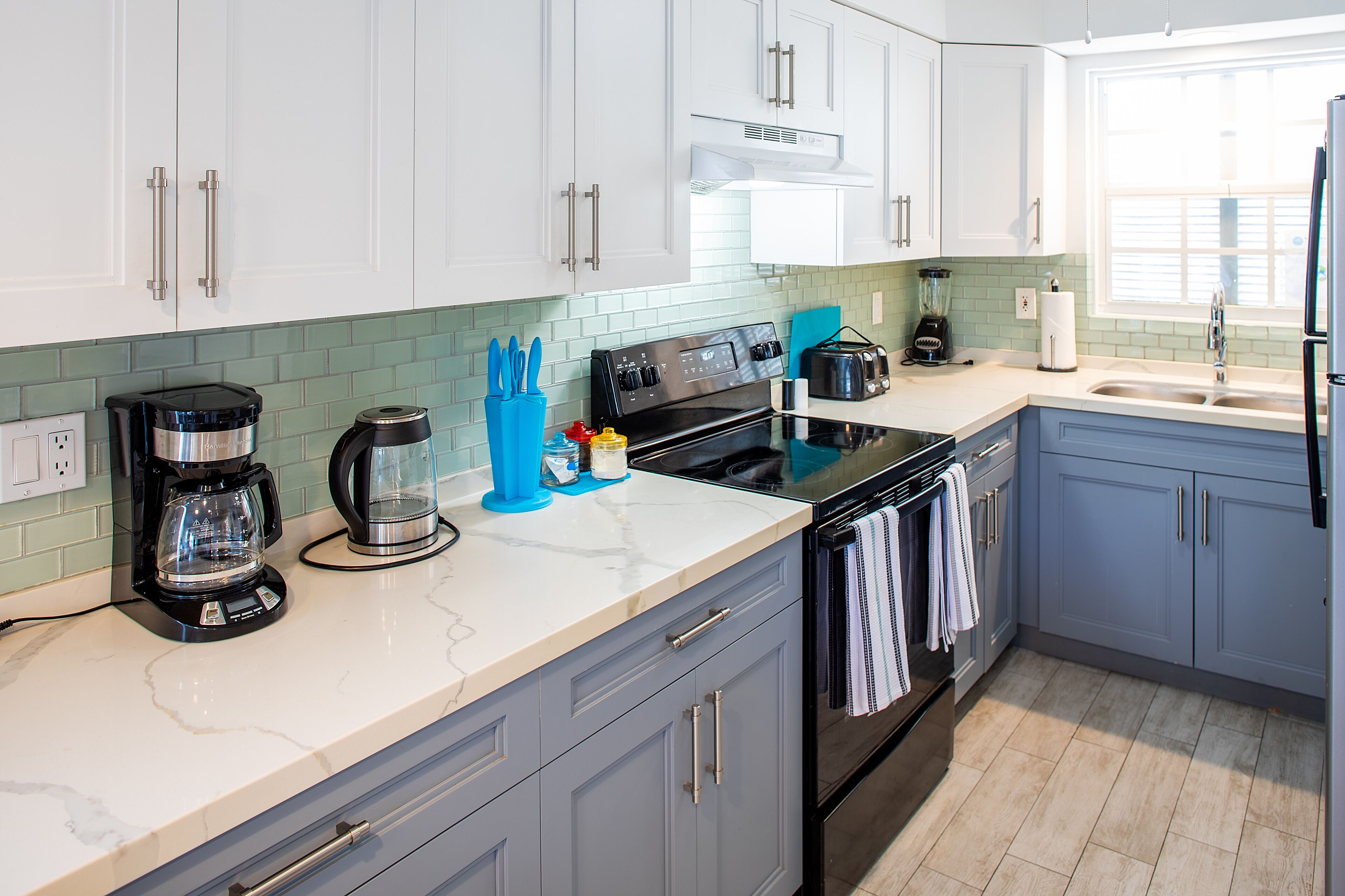 A modern kitchen with white cabinets, a black stove, and a sink.
