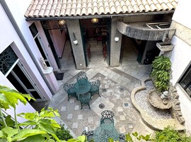 A courtyard with a tiled roof, outdoor seating, and a decorative fountain.