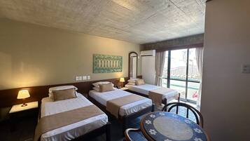 A hotel room with two single beds, a small round table, and a window with curtains.