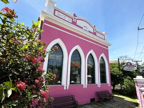 Un bâtiment rose doté de trois fenêtres en arc de cercle et d’une enseigne indiquant : « Hôtel Catharina Paraguacu ».