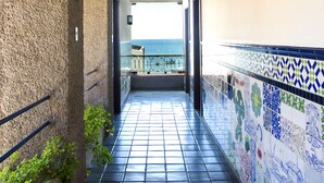 Un pasillo con suelo de baldosas, vista al mar y pared de baldosas con diseño geométrico.