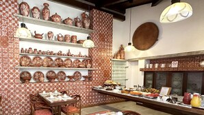 Comedor con varias mesas dispuestas para el desayuno, decorado con vajilla y objetos de cerámica.