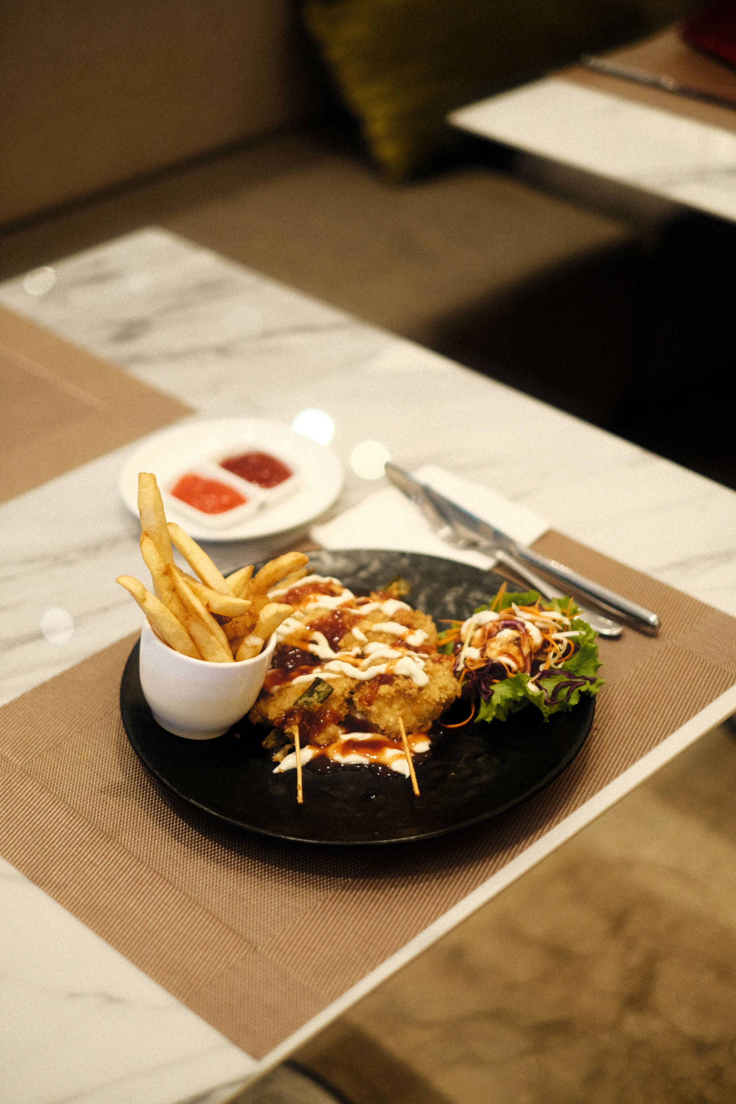 A plate of food with fries and a salad on a table.