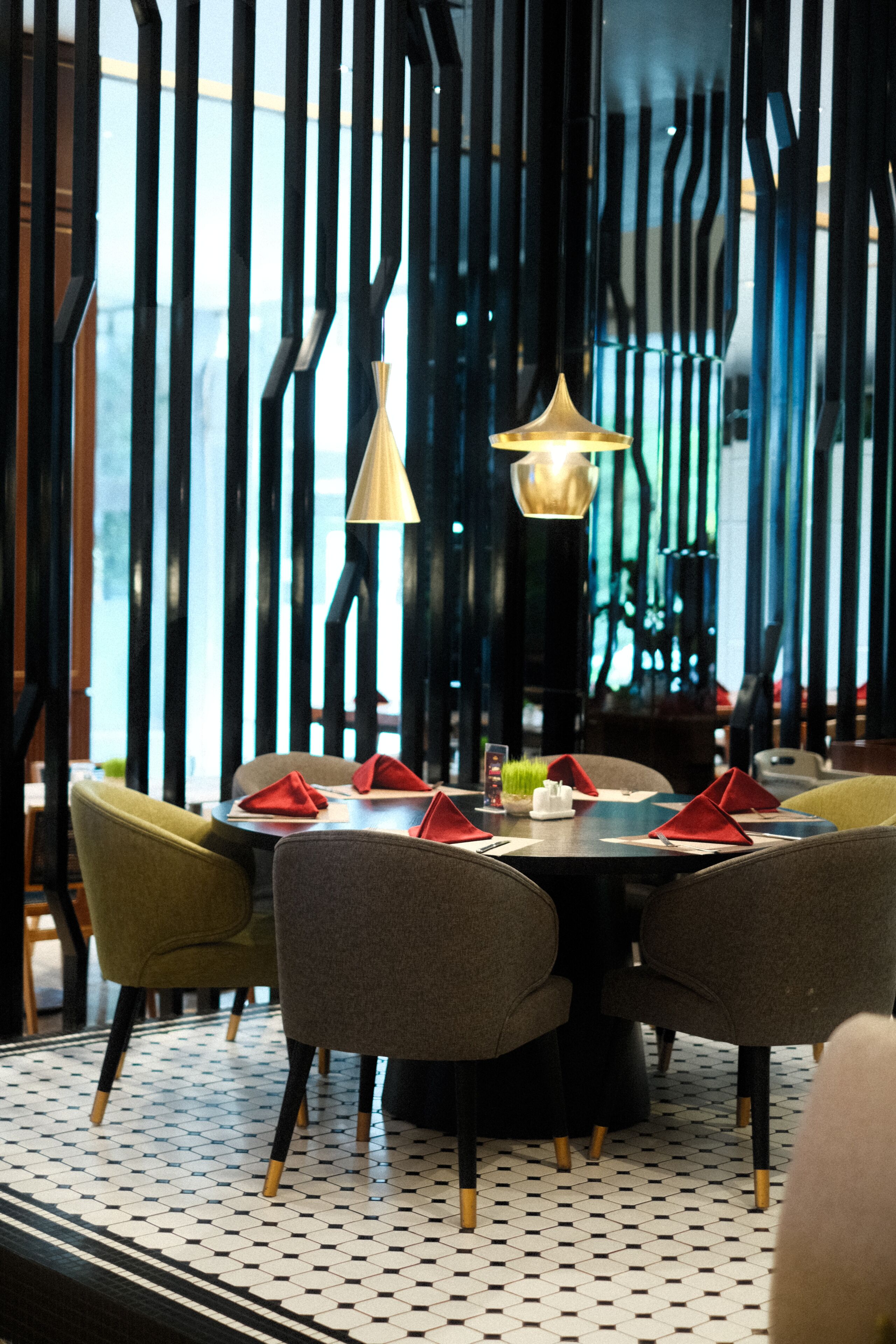 A restaurant interior with a round table, grey chairs, and a patterned floor.