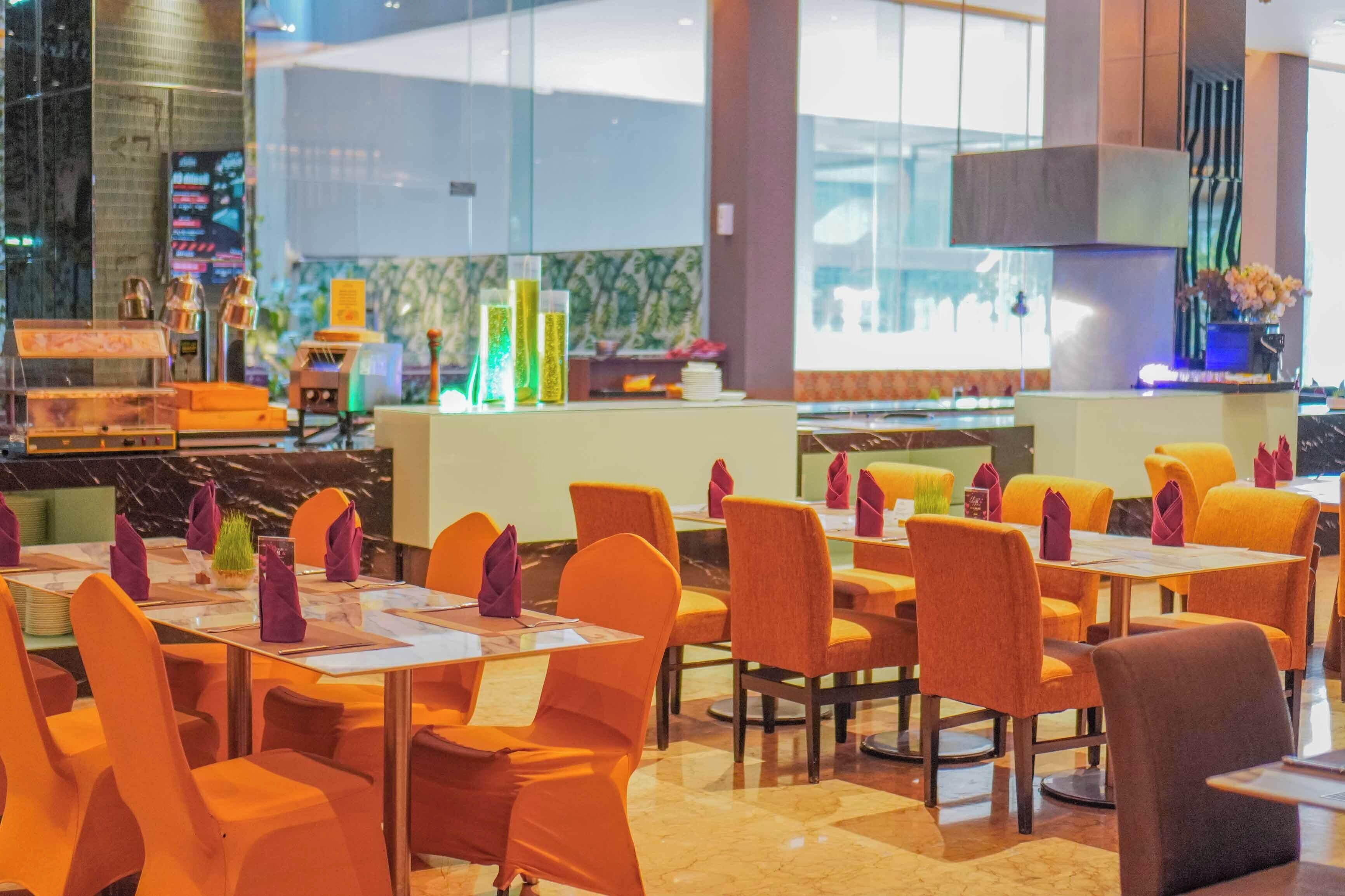 A restaurant with orange chairs and tables, a bar area, and a modern interior design.