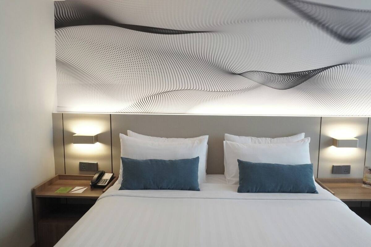 Ett hotellrum med en stor säng, två sängbord och en unik takdesign.