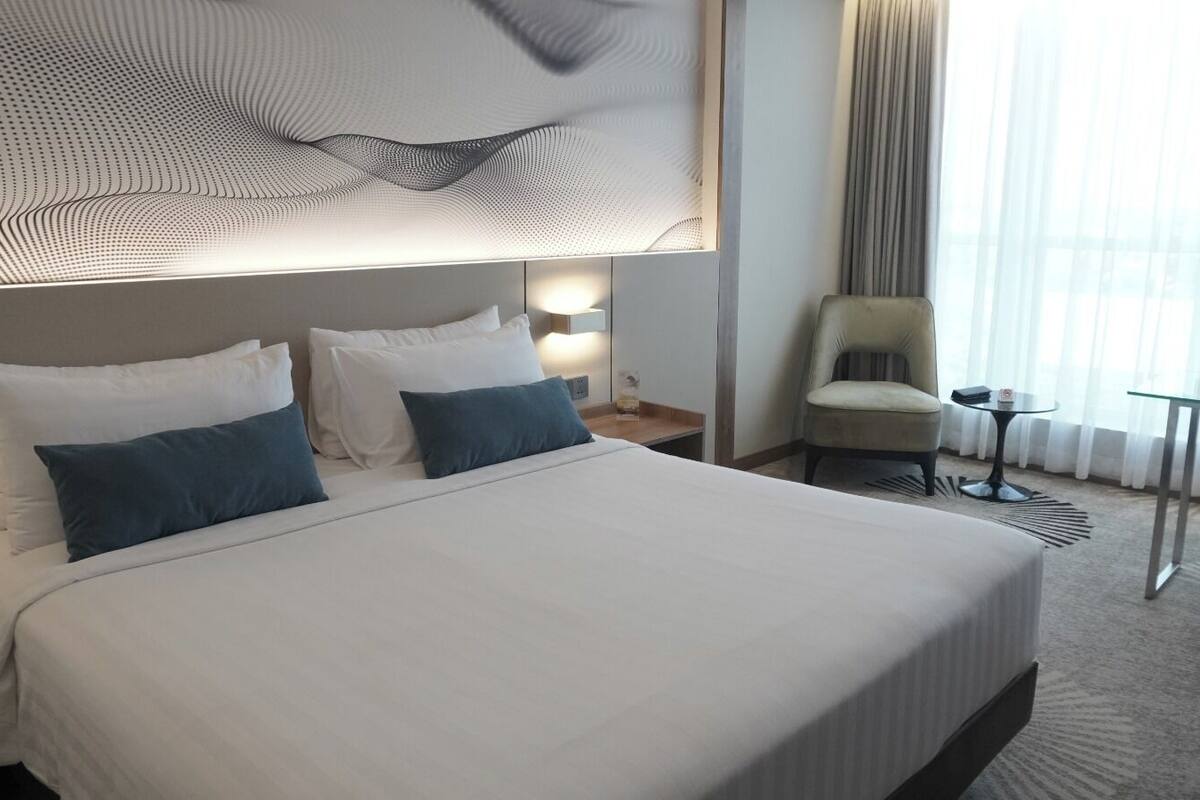 Ett hotellrum med en stor säng, en stol, ett litet bord och ett skrivbord.