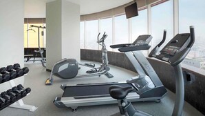 Un gimnasio con cintas de correr, mancuernas y equipamiento de ejercicio.