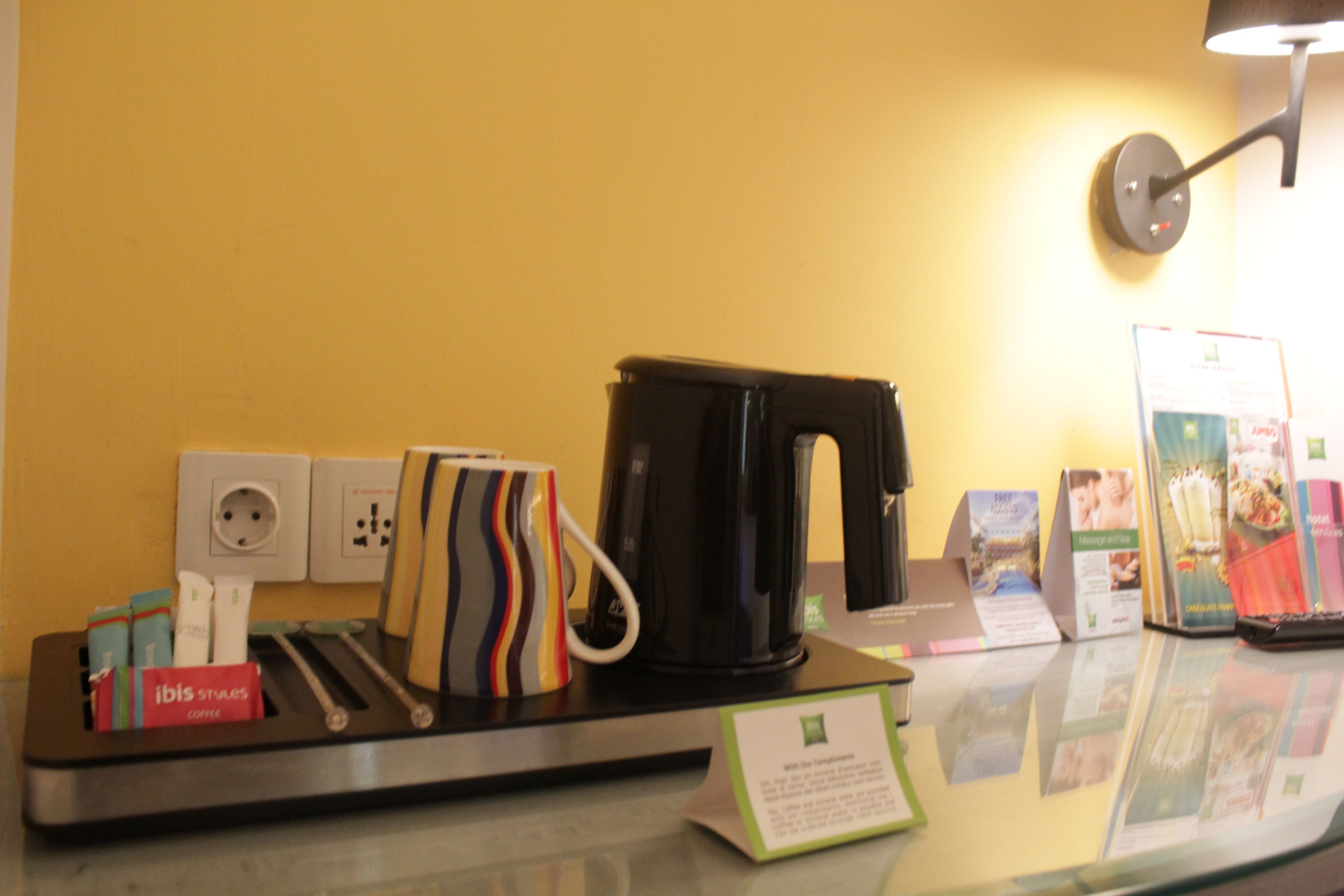 A coffee station with a coffee maker, a striped mug, and a sign indicating the coffee type.
