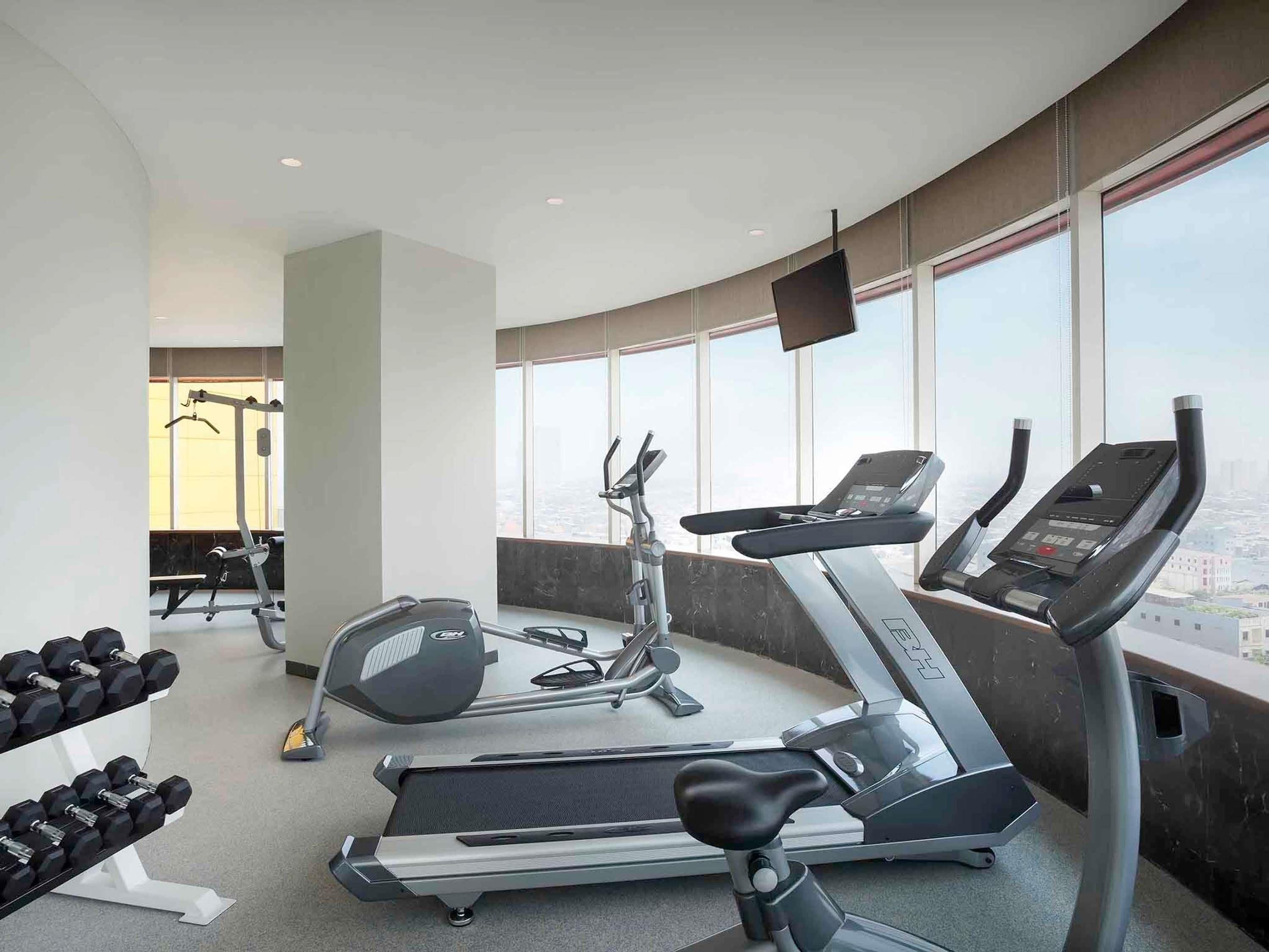 Un gimnasio con cintas de correr, mancuernas y equipamiento de ejercicio.