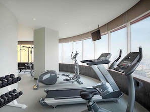 Un gimnasio con cintas de correr, mancuernas y equipamiento de ejercicio.