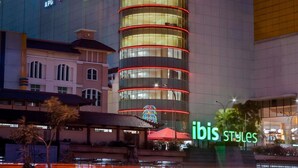 A hotel with a modern design, featuring a prominent curved facade with illuminated red lines. - ibis Styles Jakarta Mangga Dua Square (Jakarta)