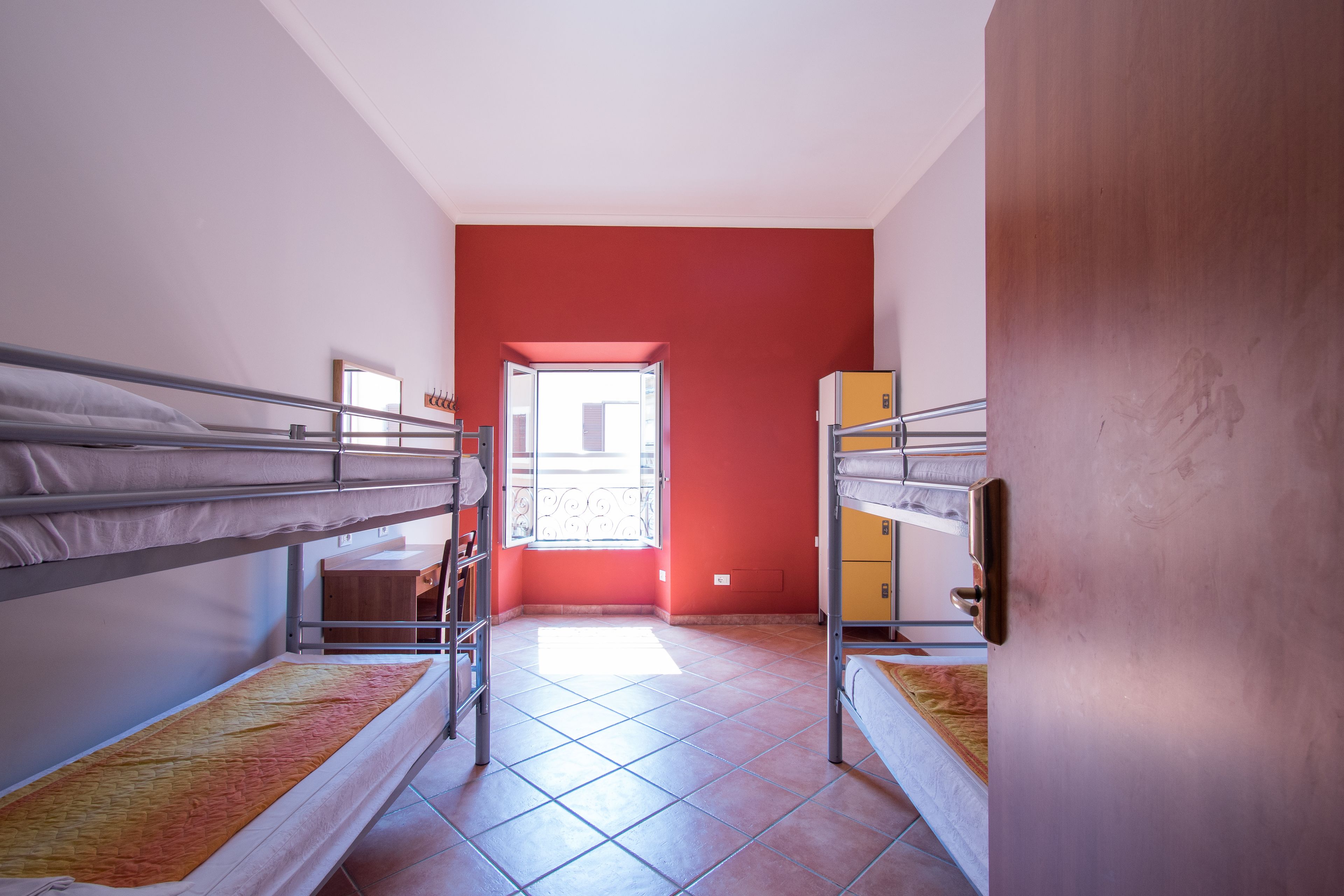 Ein Schlafsaalzimmer mit Etagenbetten, einem Fenster mit Blick und einer Tür zu einem weiteren Raum.